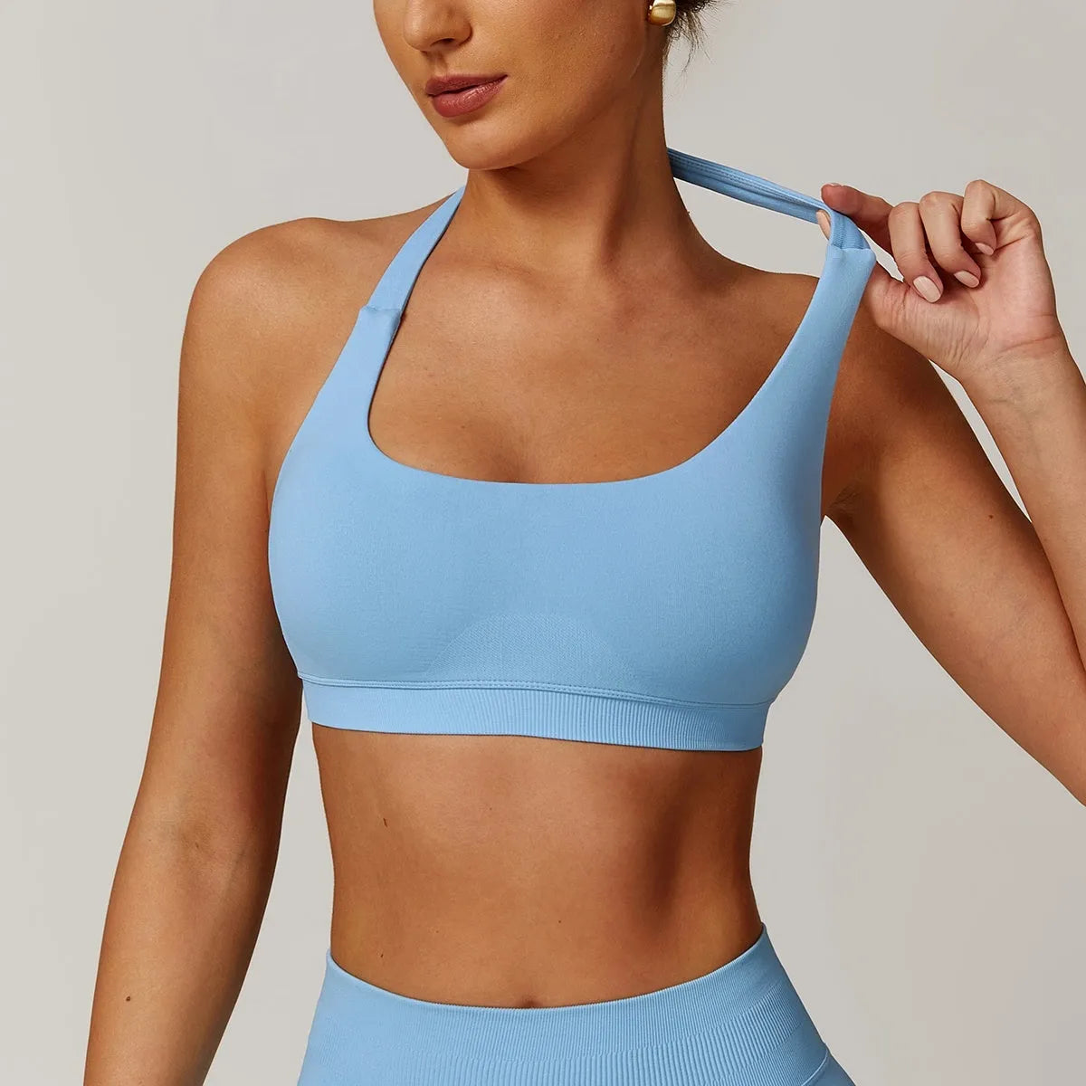 Women's black halter neck sports bra for yoga, shown from the front, with removable pads and a backless design.