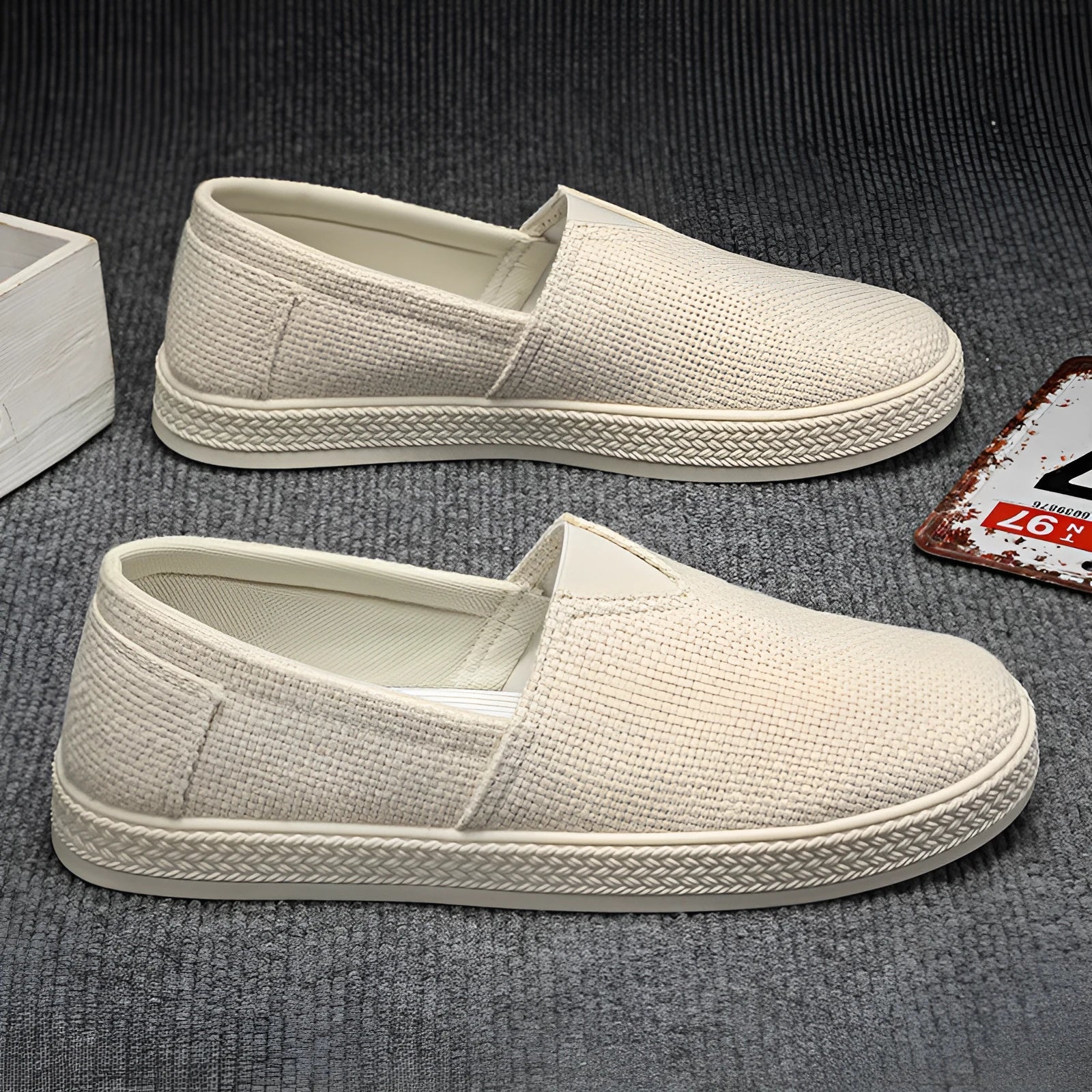 Men's beige linen canvas slip-on shoes with round toe and shallow cut design on a grey background.