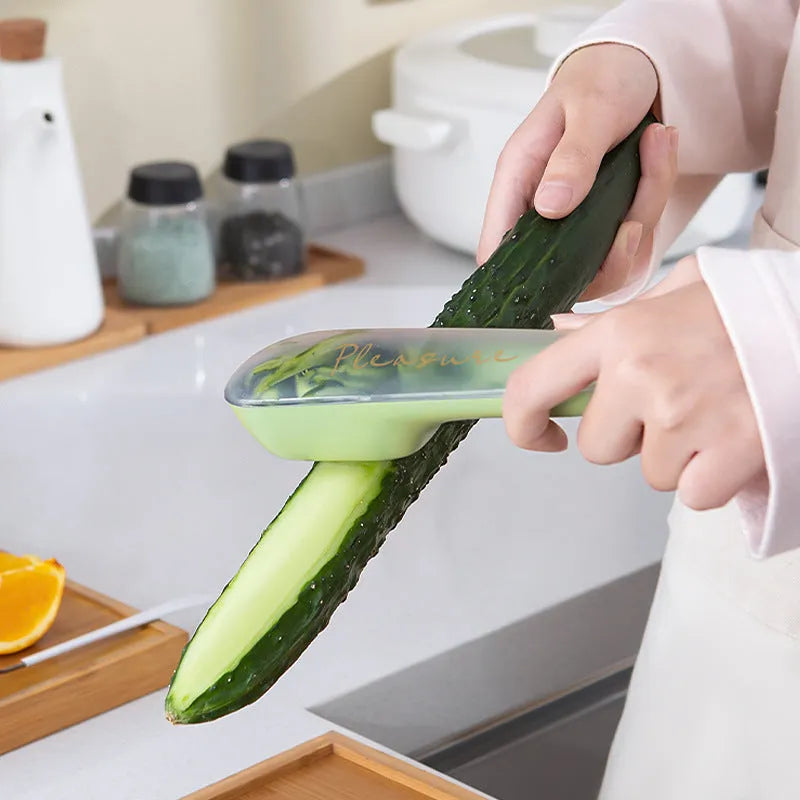 Dark green kitchen peeler with storage tube and stainless steel blade on a worktop.