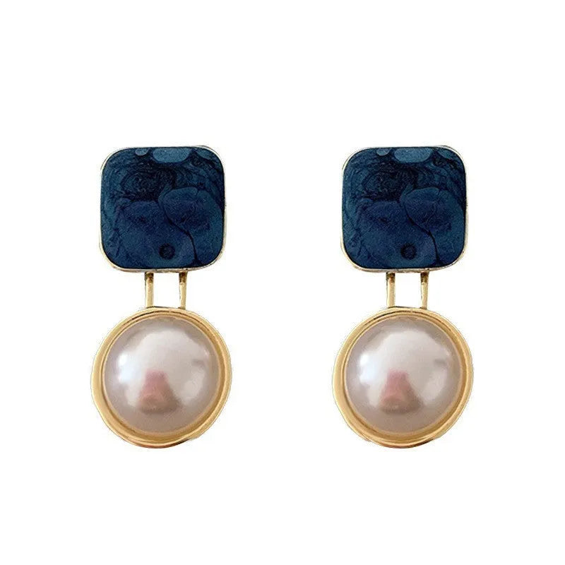 Red and blue geometric alloy stud earrings with pearl centre on neutral background