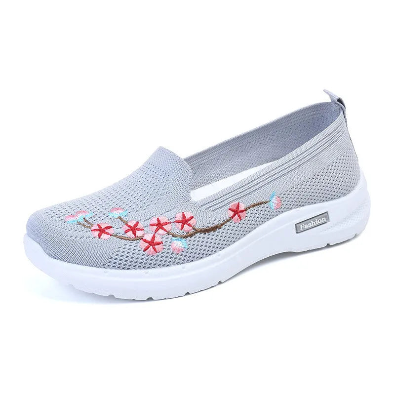 Women's embroidered floral flat pump in woven fabric with a low heel and round toe.