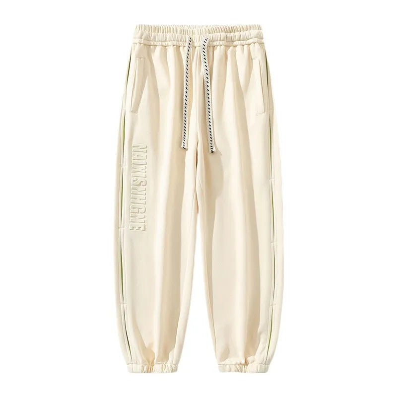 Man wearing loose-fit black trousers with printed stitching detail and a banded ankle cuff.