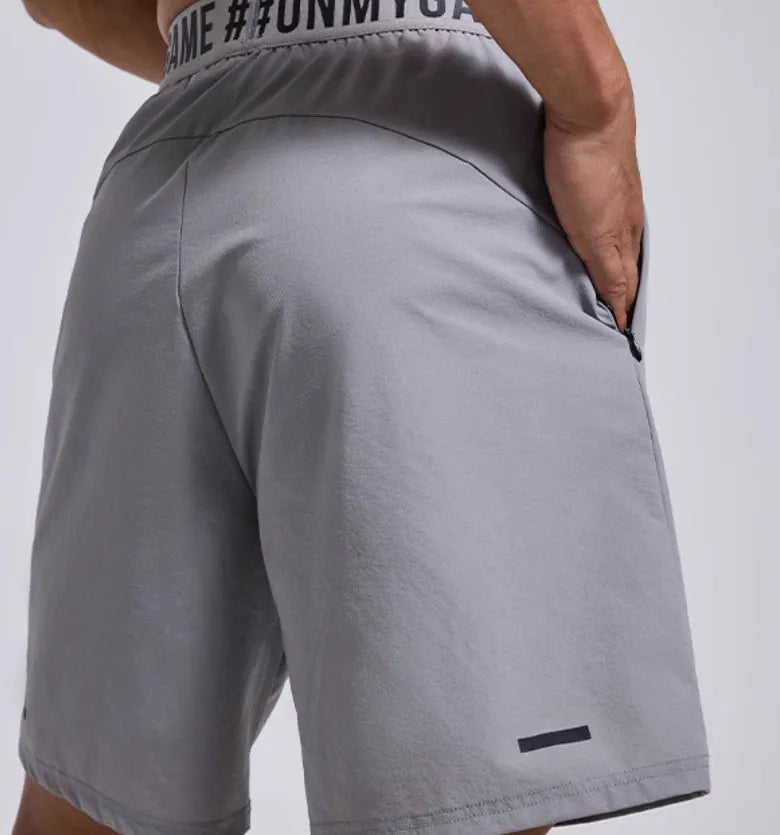 Man modelling black loose-fit cropped sports shorts with letter detail and an elastic waistband.