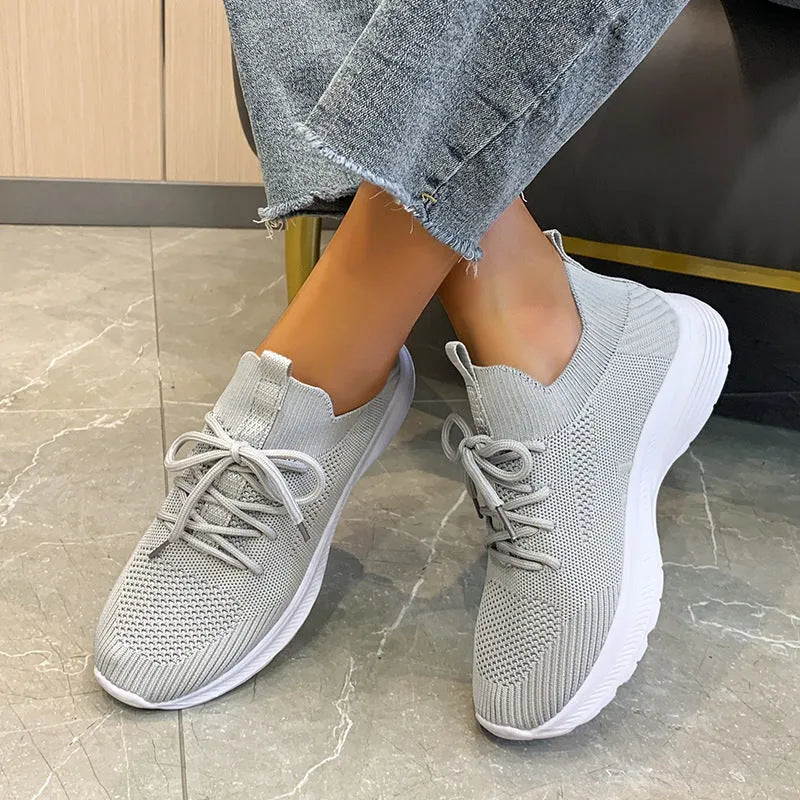 Women's low-top mesh running shoes in creamy white with a flat rubber sole and distinctive English muffin heel detail.