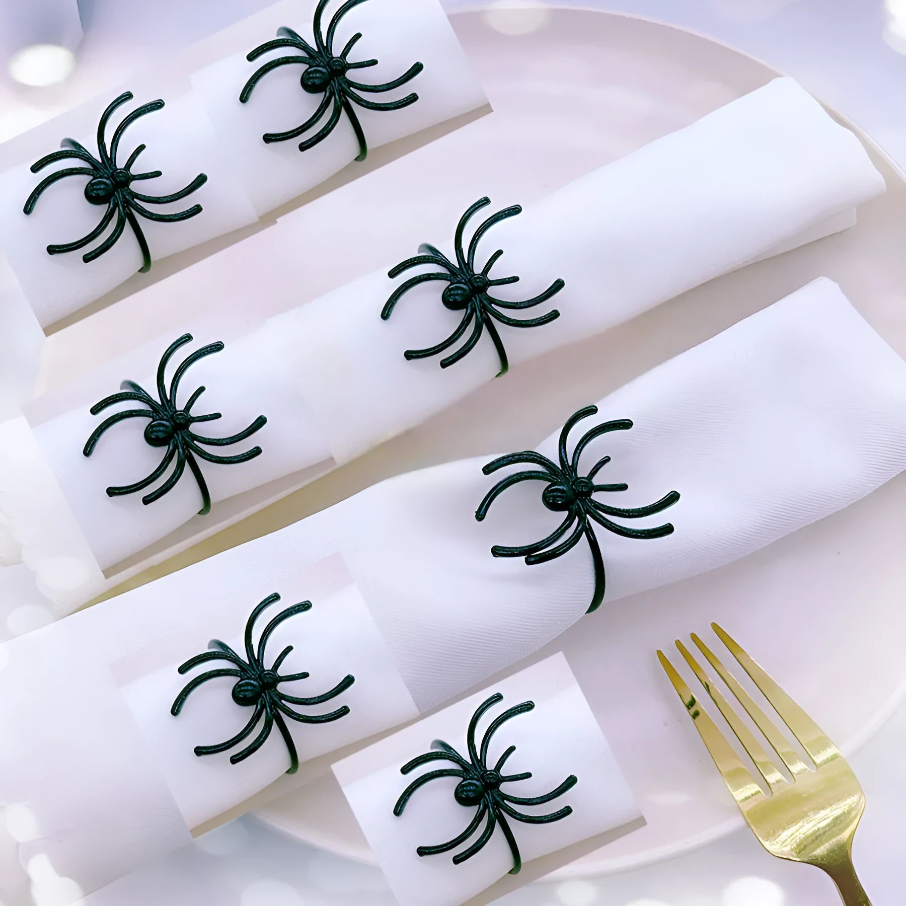 Set of six black alloy spider-shaped napkin rings on a dark tablecloth.