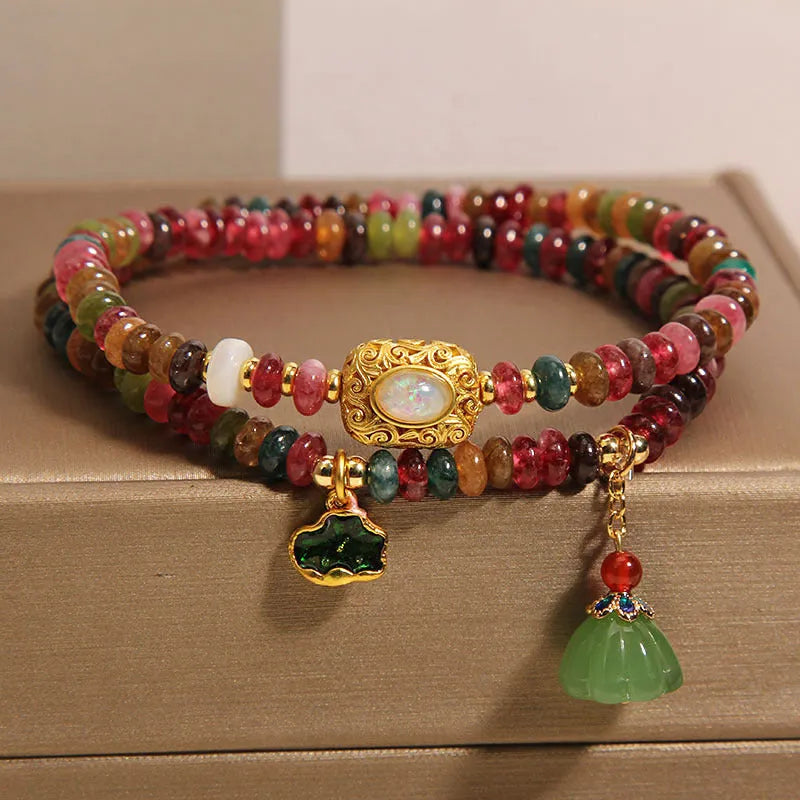 Rainbow tourmaline abacus beads double ring bracelet with lotus seedpod and flower shapes, on white background