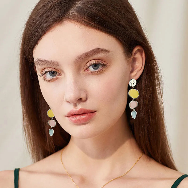 A pair of simple disc-shaped earrings with a morandi three-colour oil-drip finish and sterling silver posts.