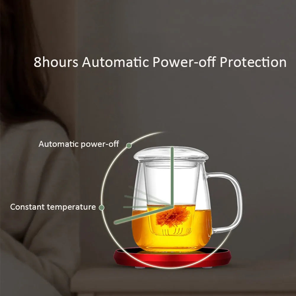 Black USB heating coaster with tempered glass plate on a desk next to a coffee mug