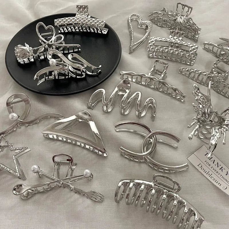 Silver metal hair claw barrette showing one of 45 designs, such as a bow or rose, on a white background.