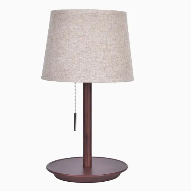 Walnut coloured solid wood bedside lamp with a white cloth lampshade and a black cable switch.