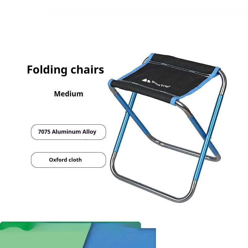 Black ethnic style aluminium alloy folding camping stool shown in use outdoors.
