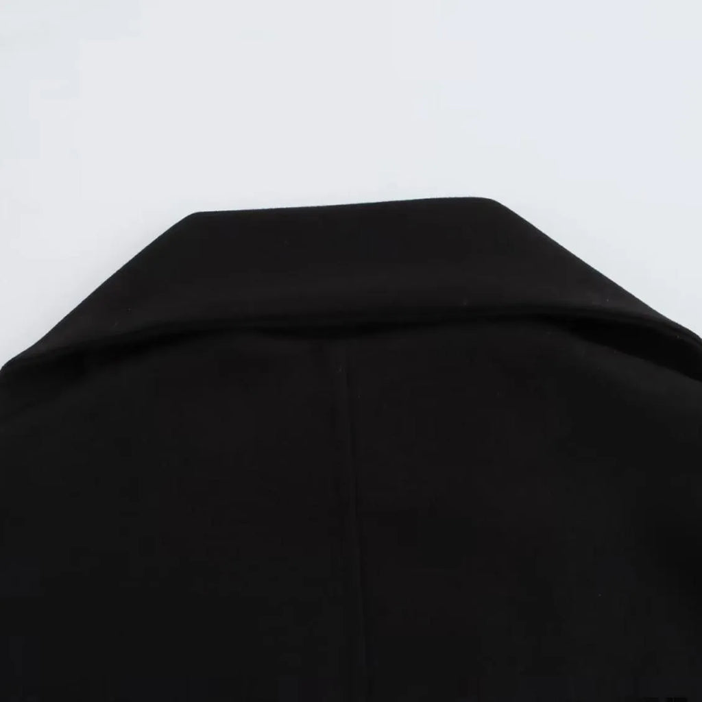 Women's long black coat with artificial fur collar, showing extended length and pocket detail.