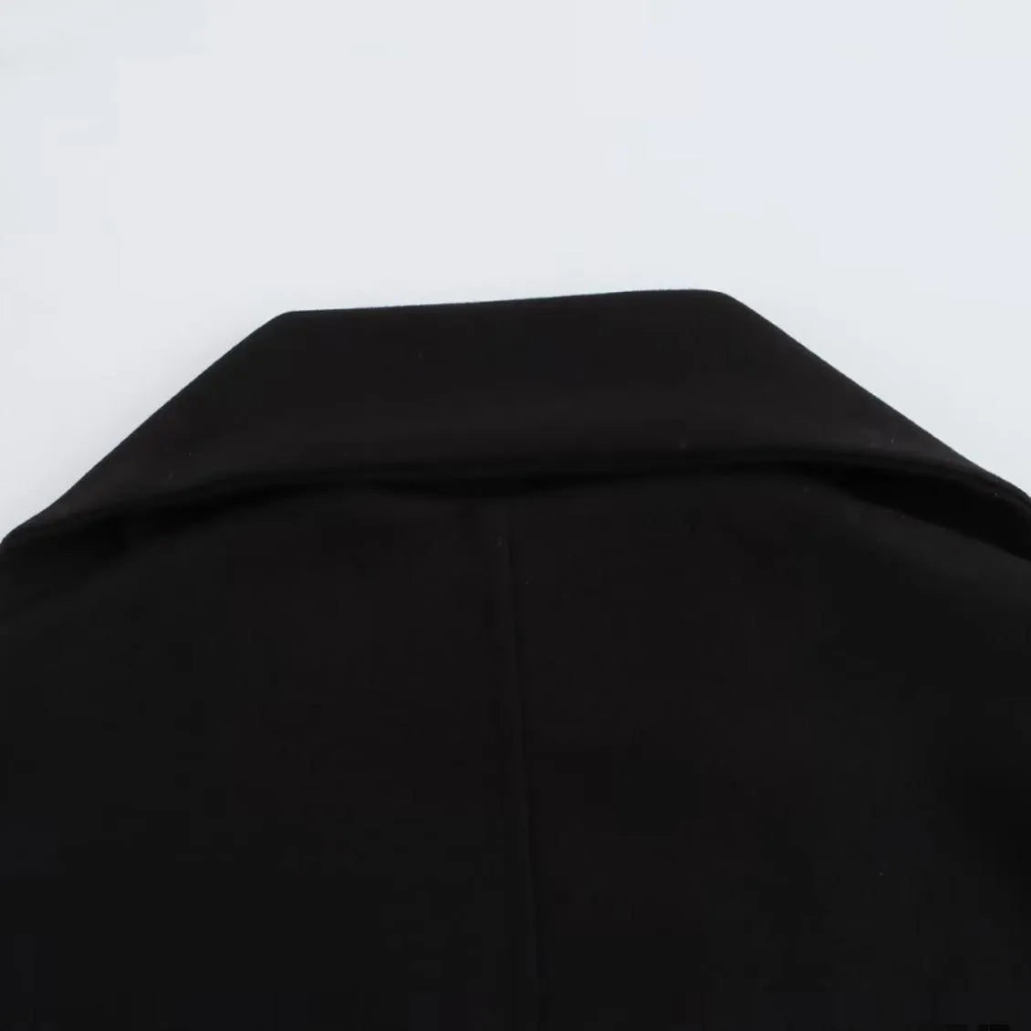 Women's long black coat with artificial fur collar, showing extended length and pocket detail.