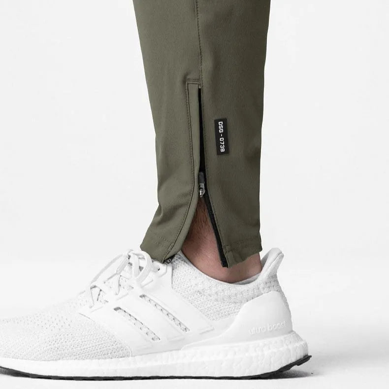 Men's loose grey fitness pants with ankle-tied cuffs laid flat, showing quick-dry polyester fabric.
