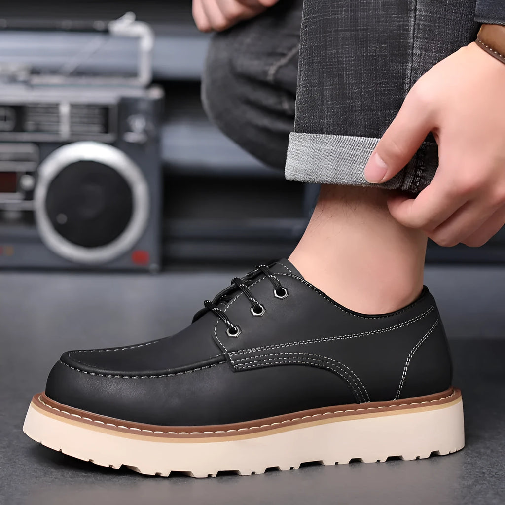 Men's black low-top Martin boots with a round toe and rubber sole on a plain background.