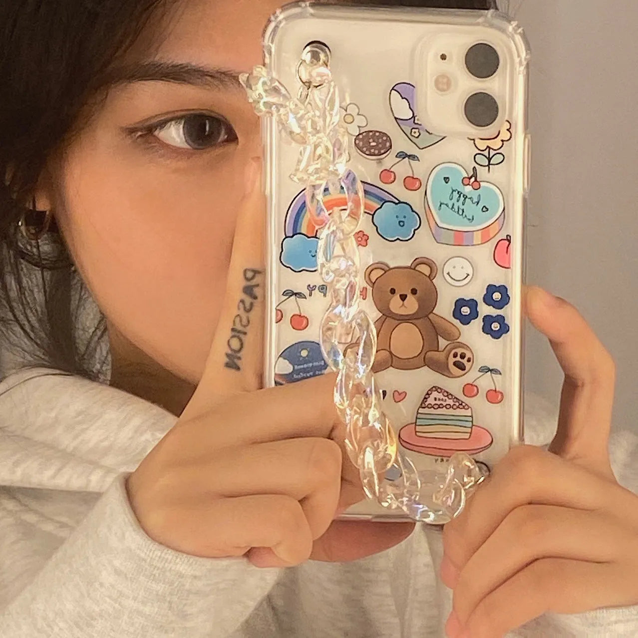 Transparent TPU iPhone case with bear chain and pendant attachment showing phone protection