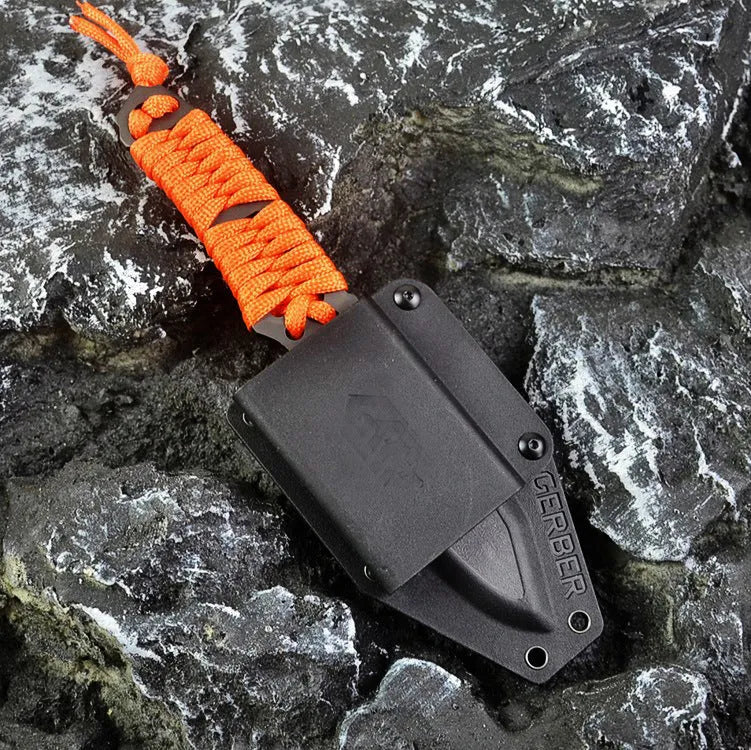 Straight camping survival knife with binding rope handle next to ABS sheath