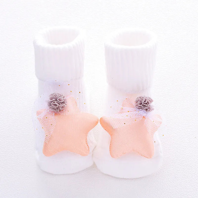 Cotton baby floor socks in various colours and patterns including pink bows, grey stars, and panda design.