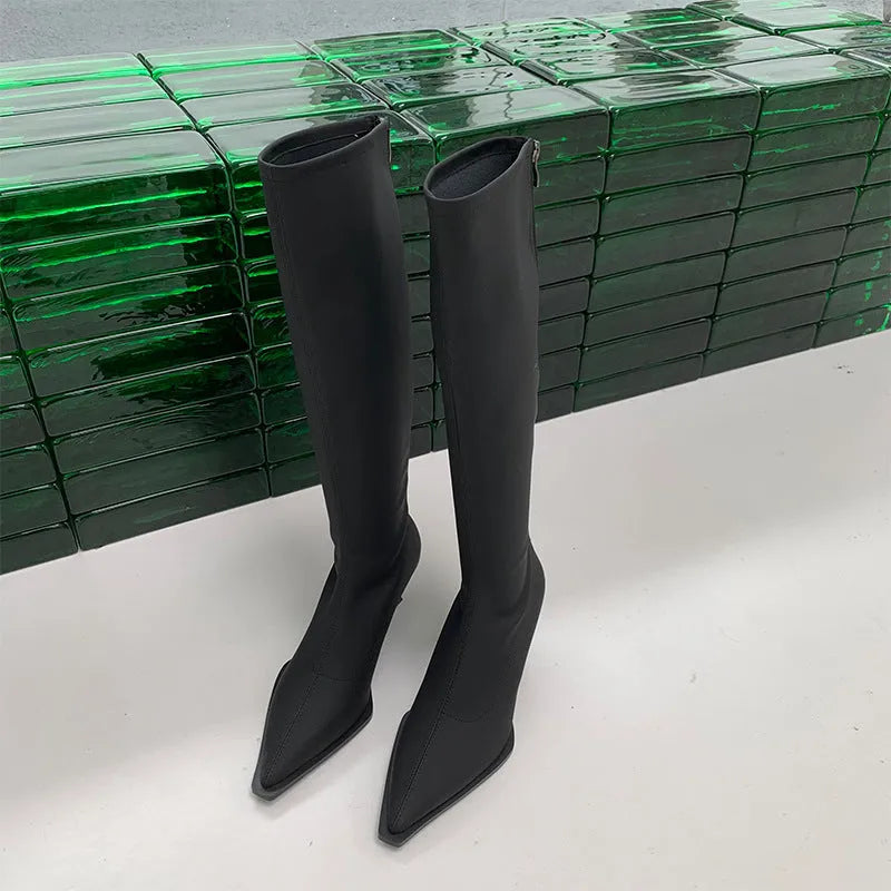 Women's black pointed toe below-knee boots with a stiletto heel and a back zipper on a plain background.