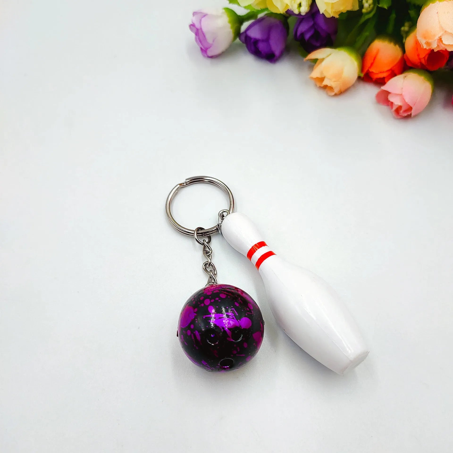 Mini bowling ball keychain in four colour options: dark red, blue, purple, green