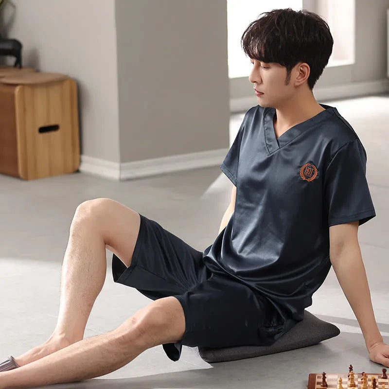 Man's loose-fitting ice silk pyjama set with short-sleeved shirt and shorts in a solid colour.