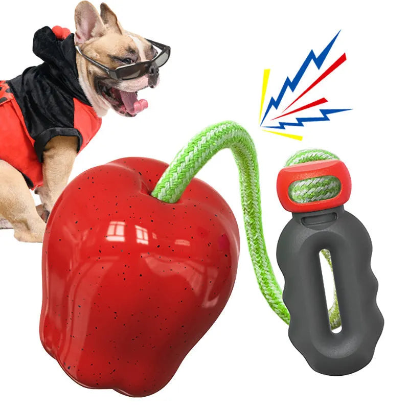Green plastic apple-shaped dog chew toy with a squeaker on a grass background.