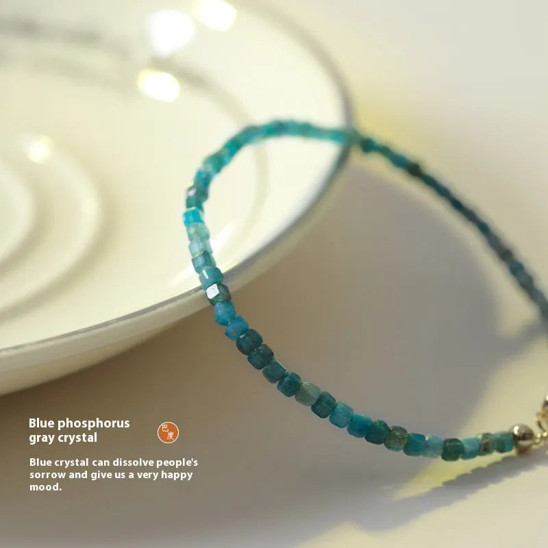 Women's blue and grey apatite crystal bracelet with diamond-cut stones on a wrist.