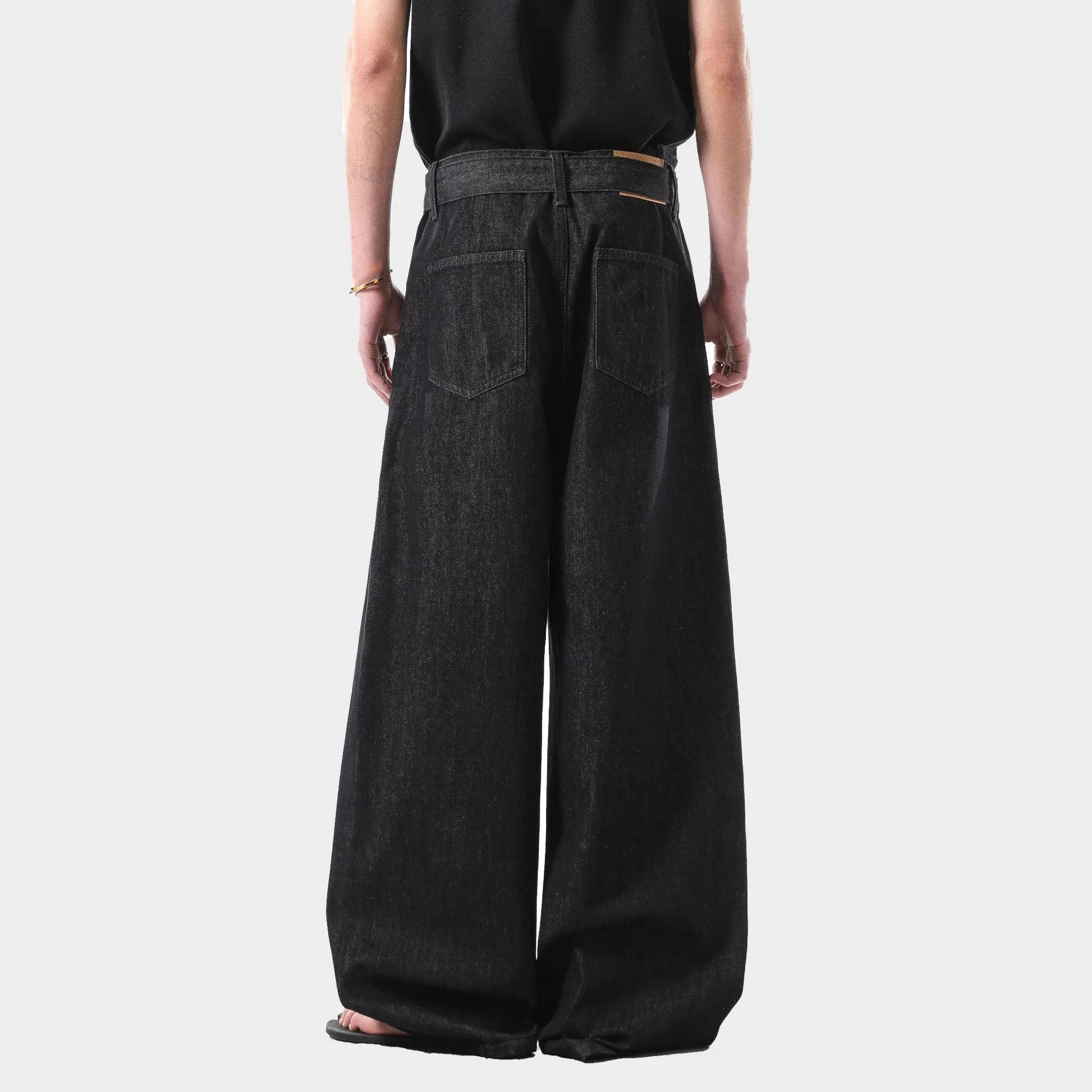 Black high waist straight leg jeans with gold details on a model.