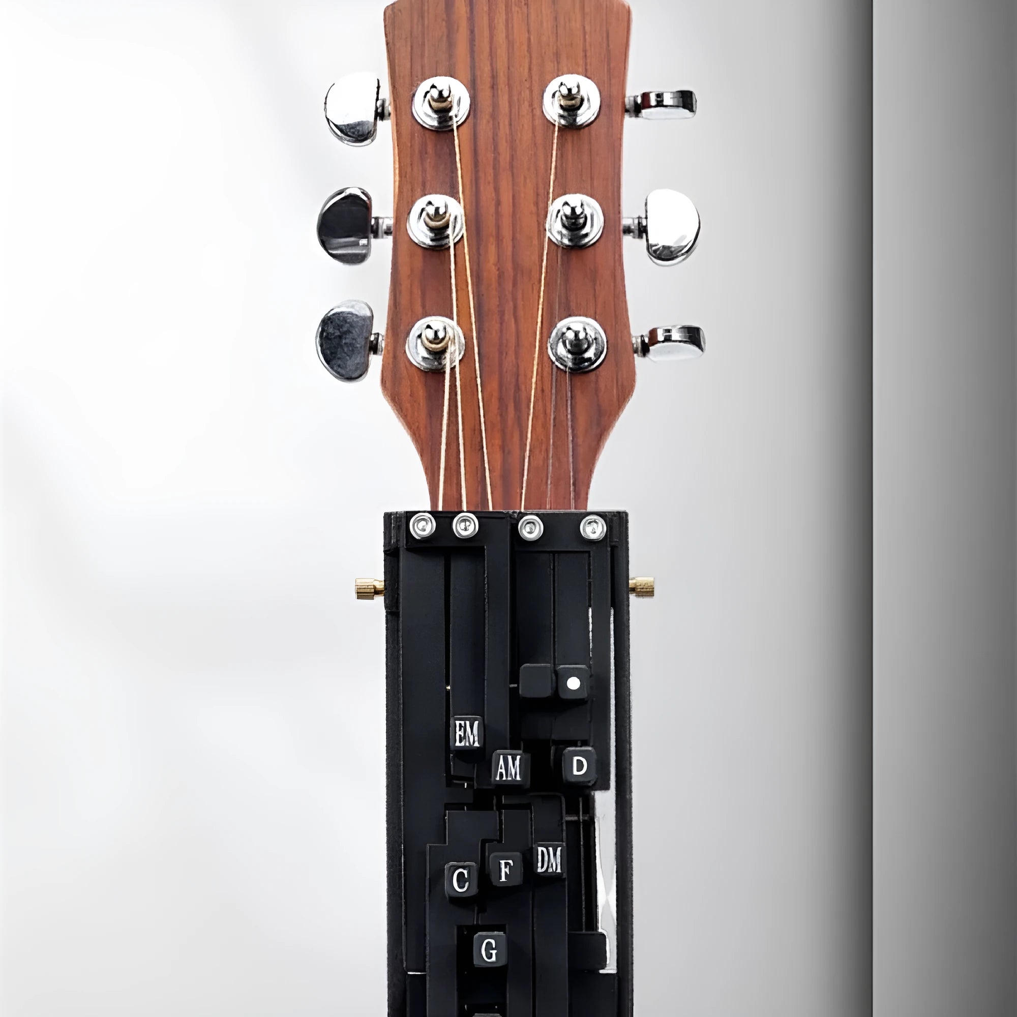 Black automatic chord practice device for novice guitar players attached to acoustic guitar