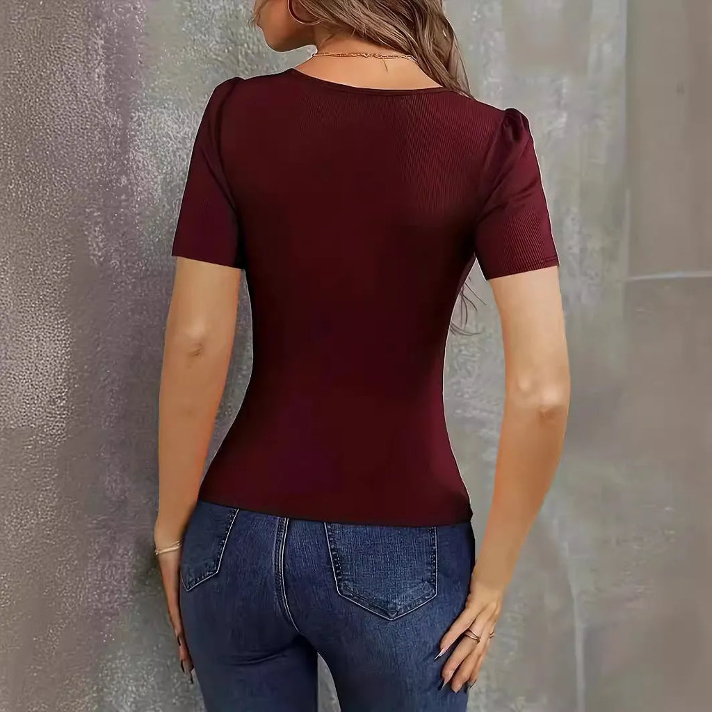 Woman wearing a wine red knitted short sleeve pullover with a low neckline and slim fit.