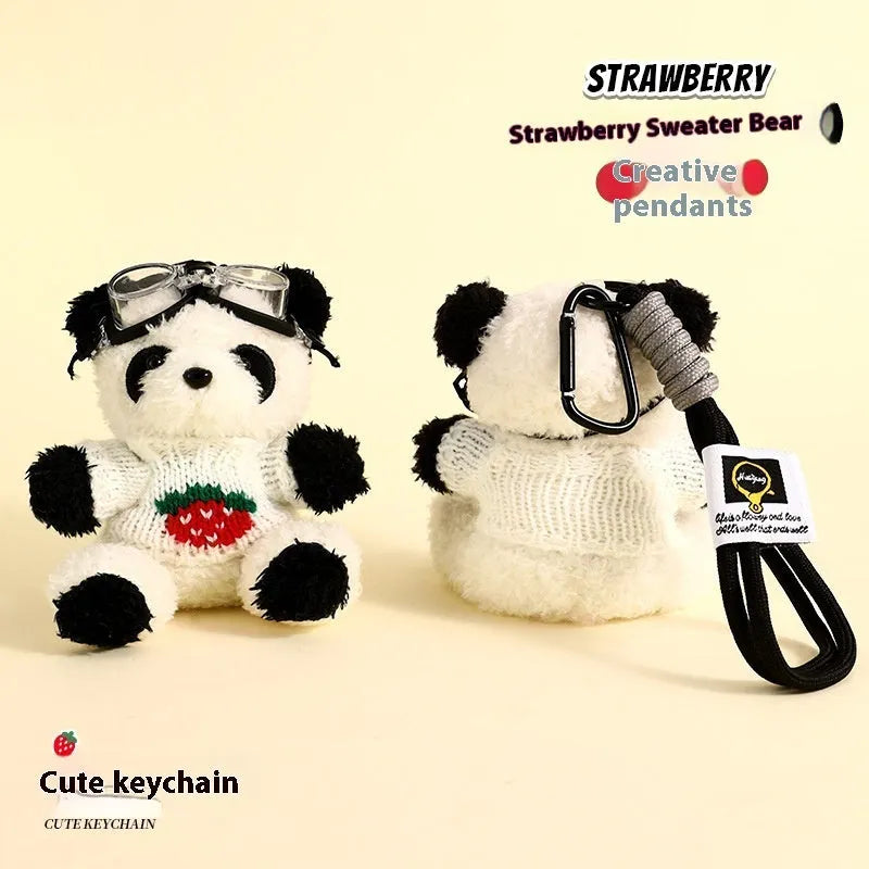 Cute plush strawberry bear doll keychain pendant on a soft surface, showing the cartoon bear with strawberry sweater design