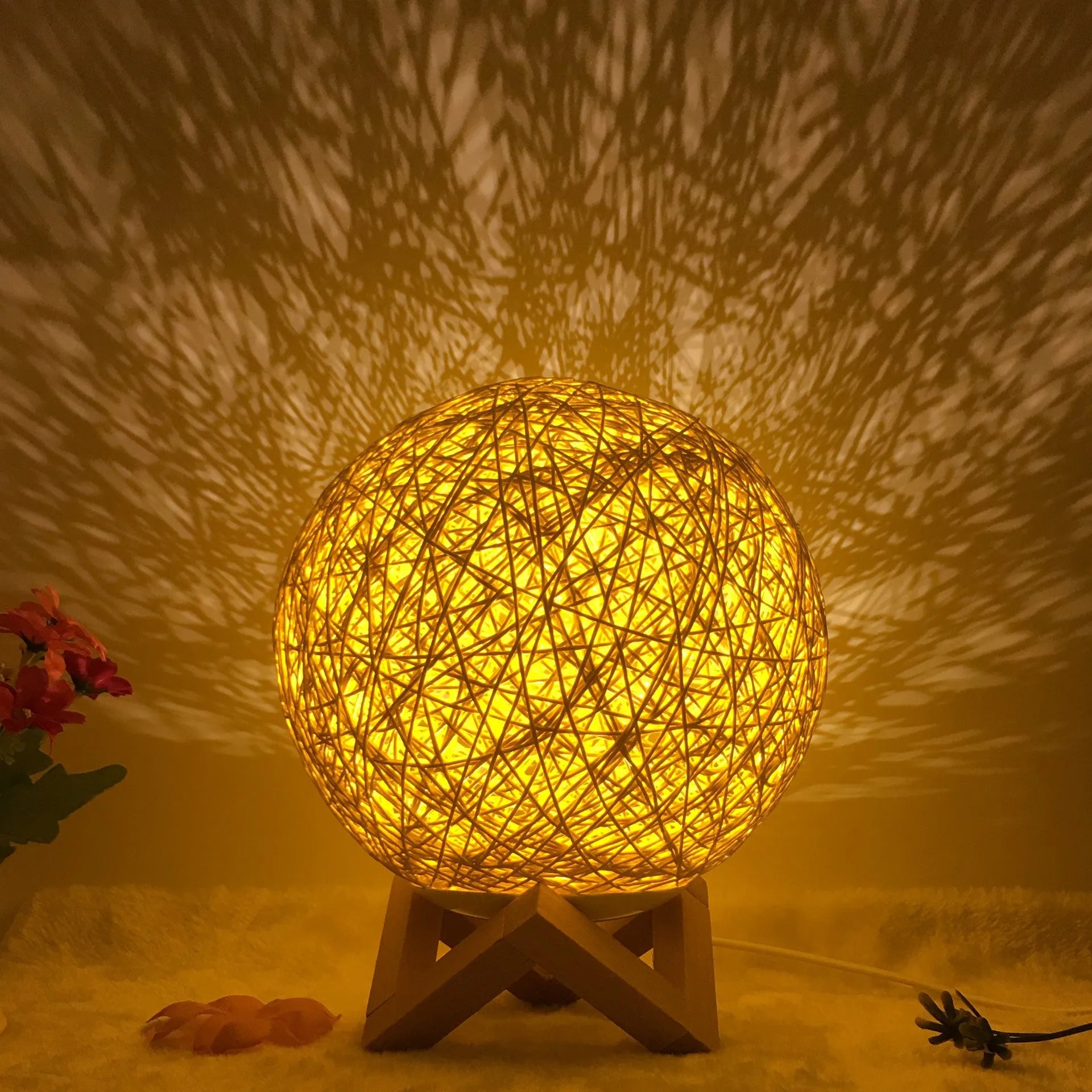 Rattan ball table lamp with woven shade and warm LED lighting on wooden surface