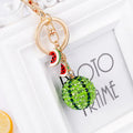 Green watermelon-shaped metal keychain on a white background.