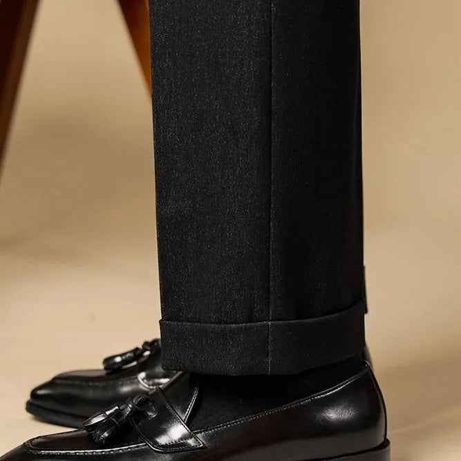 Men's black polished leather tassel loafers with rubber sole, shown from the side.