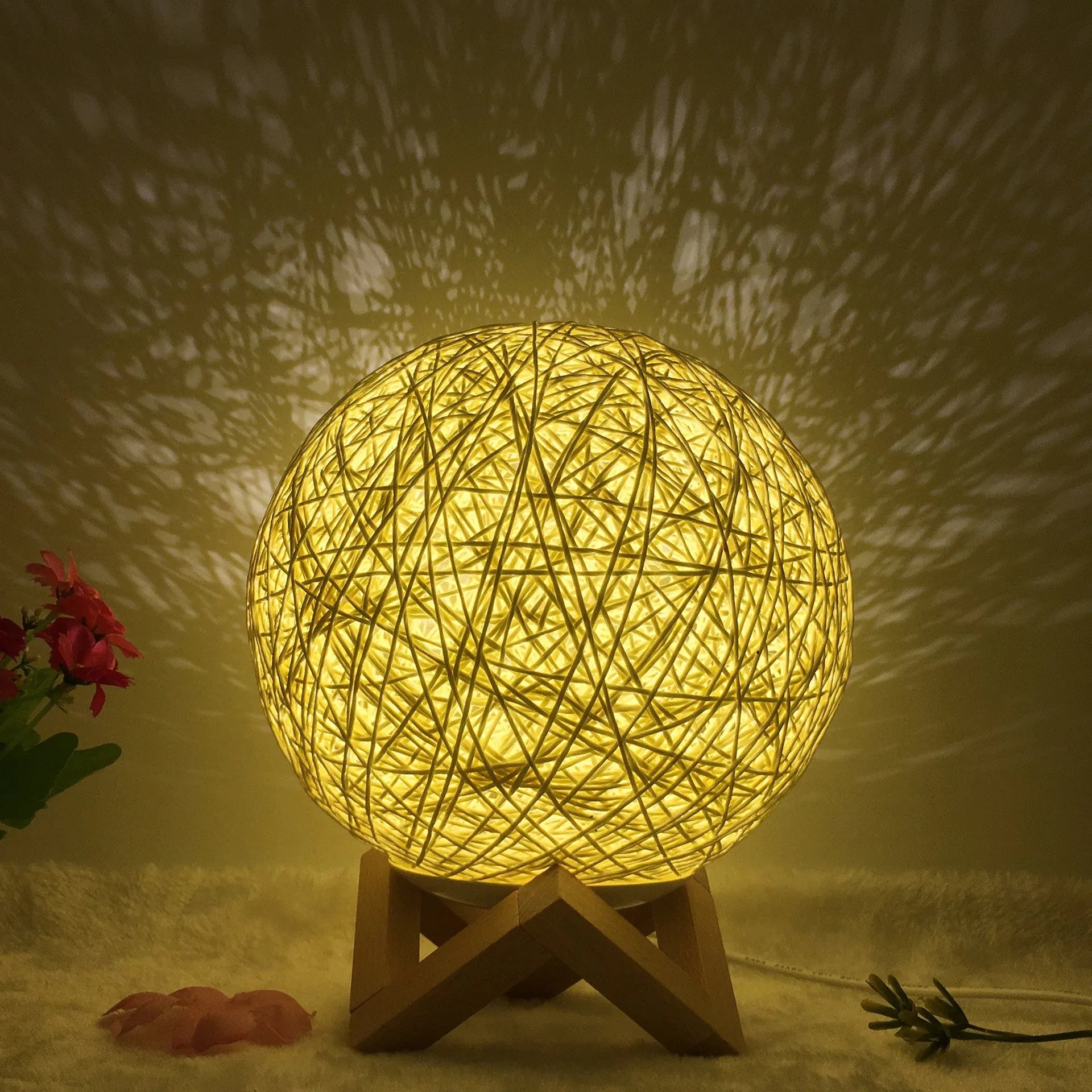 Rattan ball table lamp with woven shade and warm LED lighting on wooden surface