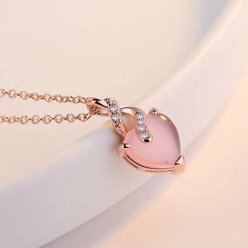 Women's pink heart crystal pendant necklace with rose gold chain on white background