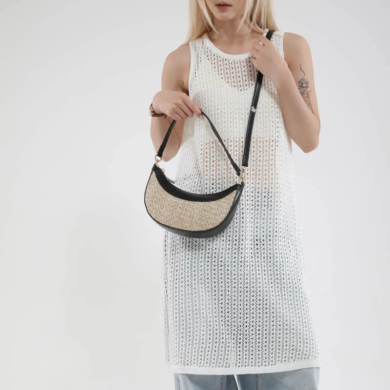 Hard structured straw dumpling shaped women's crossbody shoulder bag in black, shown with interior phone pocket.