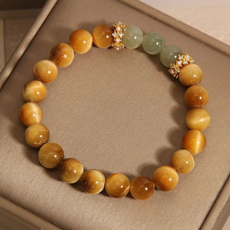 Natural yellow tiger's eye stone bracelet with gold gourd pattern on a white background.