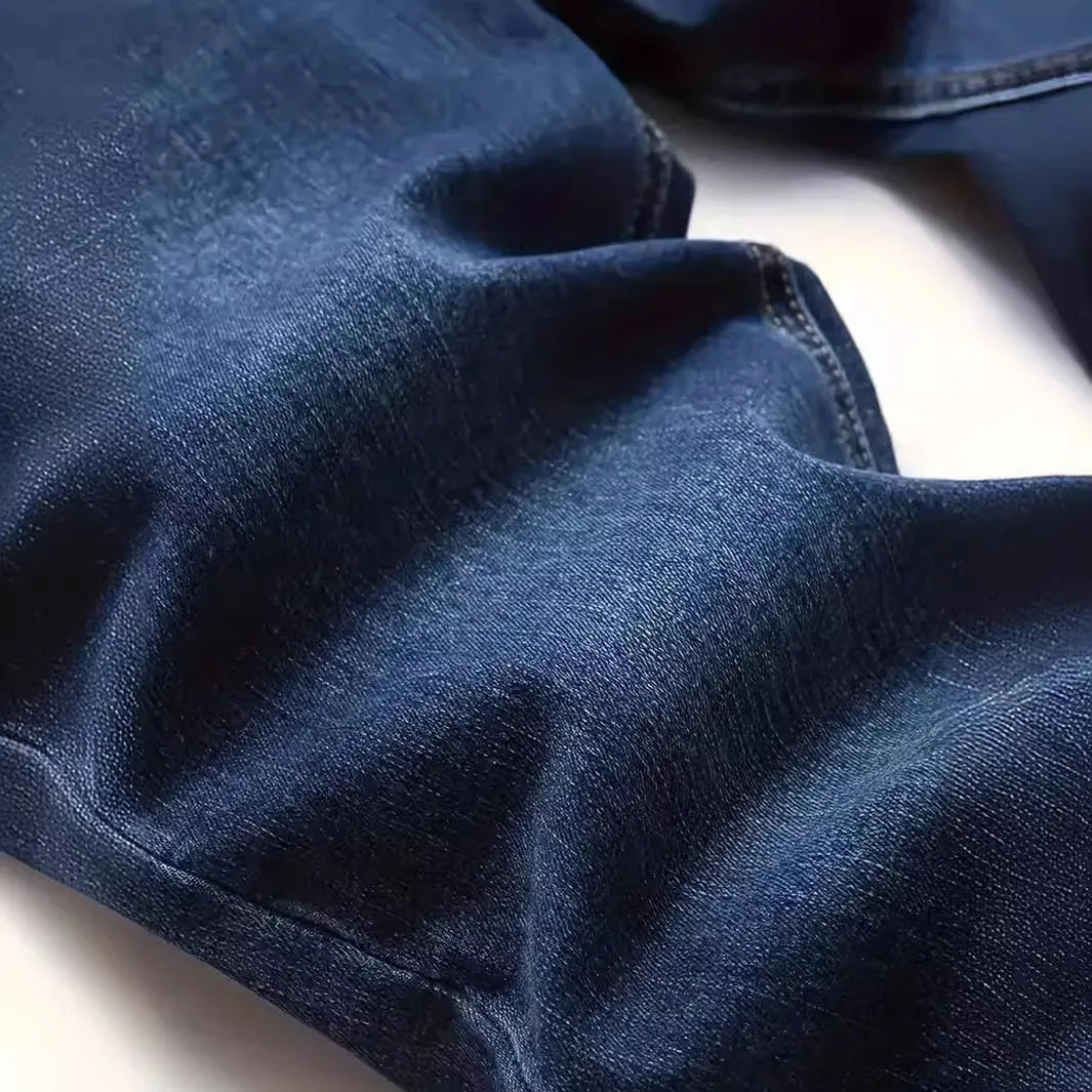Men's dark blue slim-fit skinny jeans on a hanger, showing mid-waist and zipper fly detail.