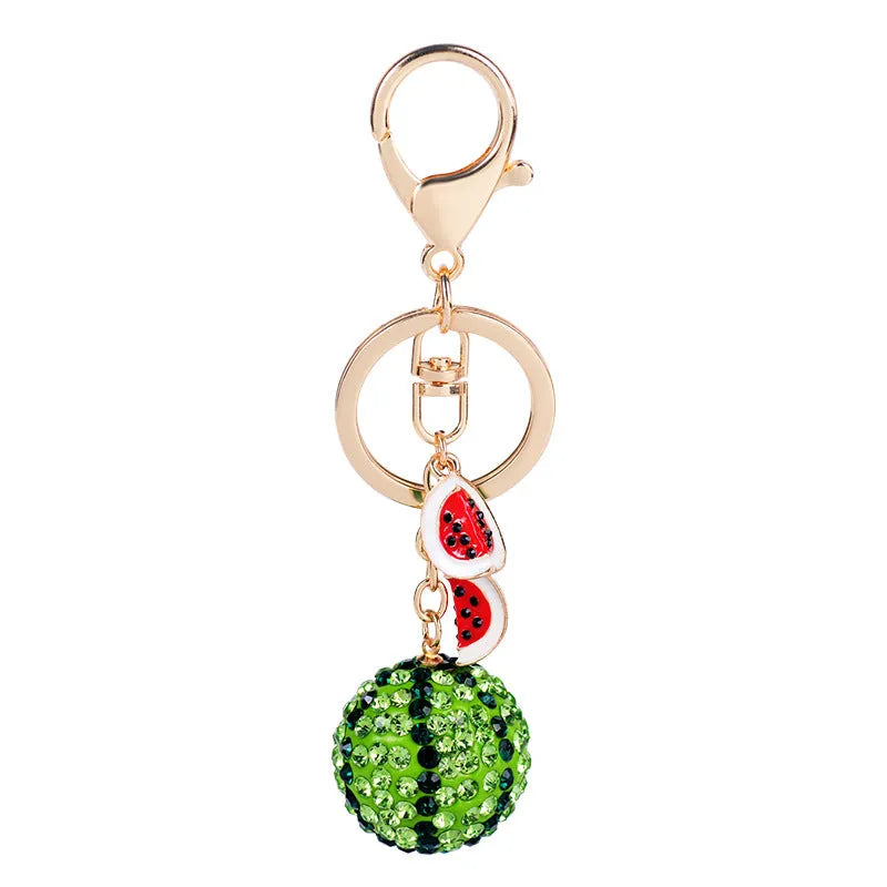Green watermelon-shaped metal keychain on a white background.