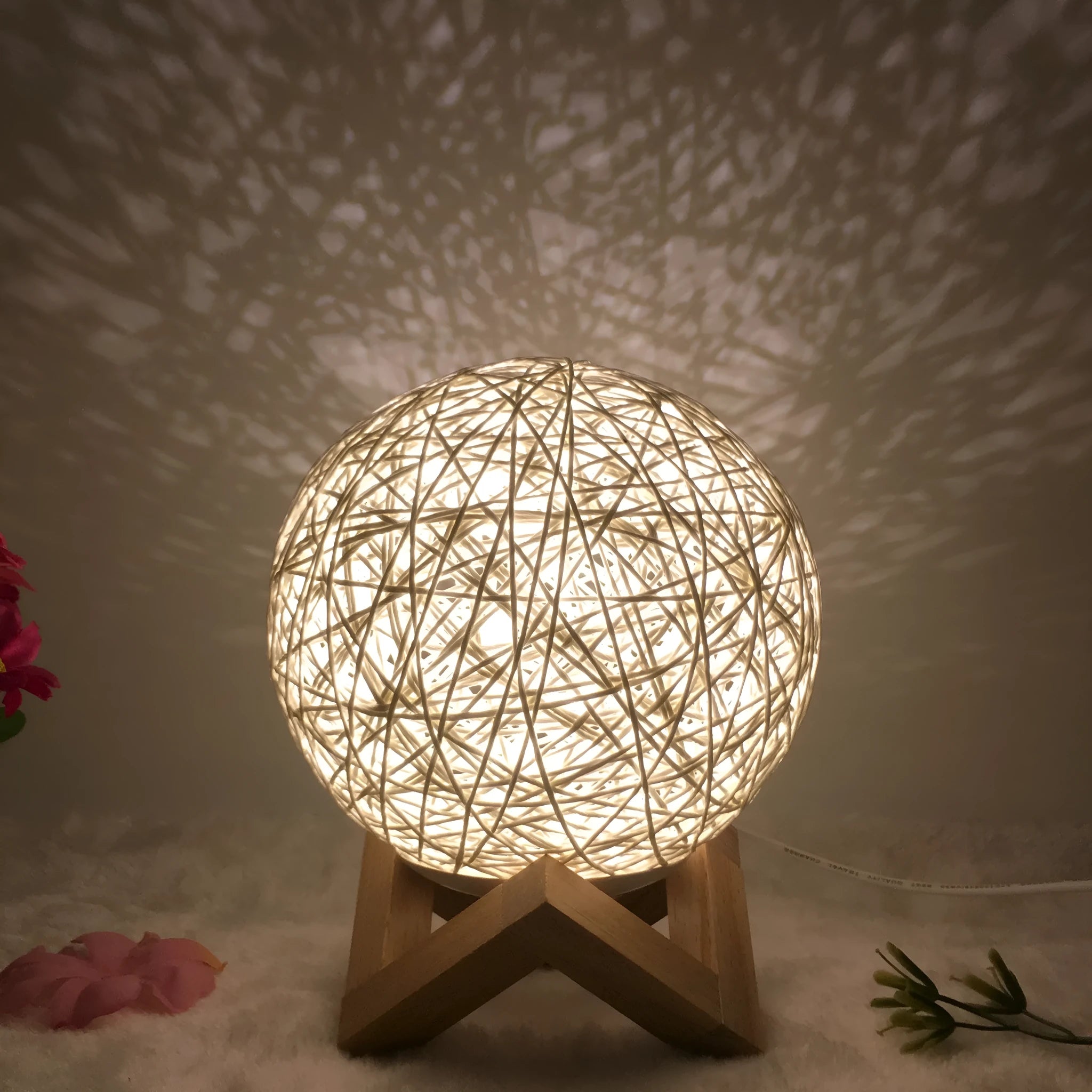 Rattan ball table lamp with woven shade and warm LED lighting on wooden surface
