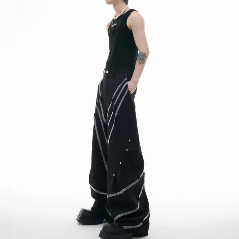Men's black trousers with metal rivet pleats and a three-dimensional tailored cut.