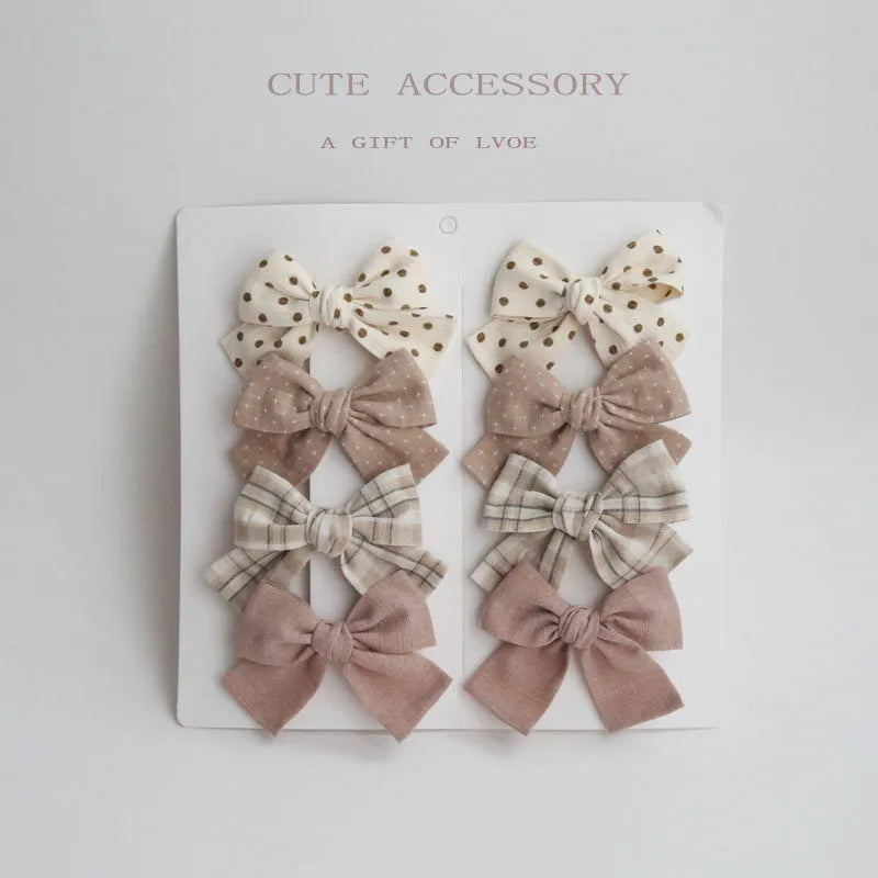 Set of children's cloth hairclips with a dovetail bow design in various colours including beige and blue flowers.