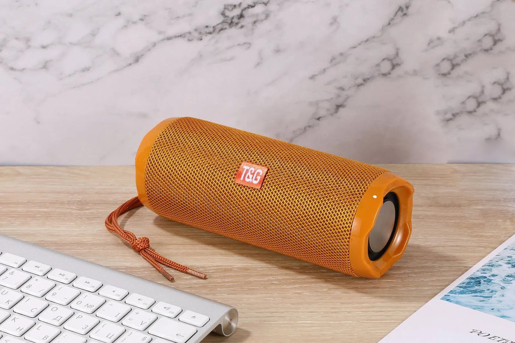 Fabric-covered portable Bluetooth speaker with a visible card slot in colours blue, black, red, gold, silver grey, and camouflage.