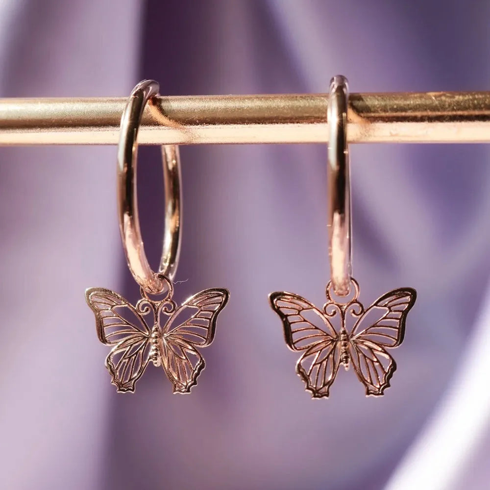 Gold copper alloy stud earrings with butterfly and bow design on white background