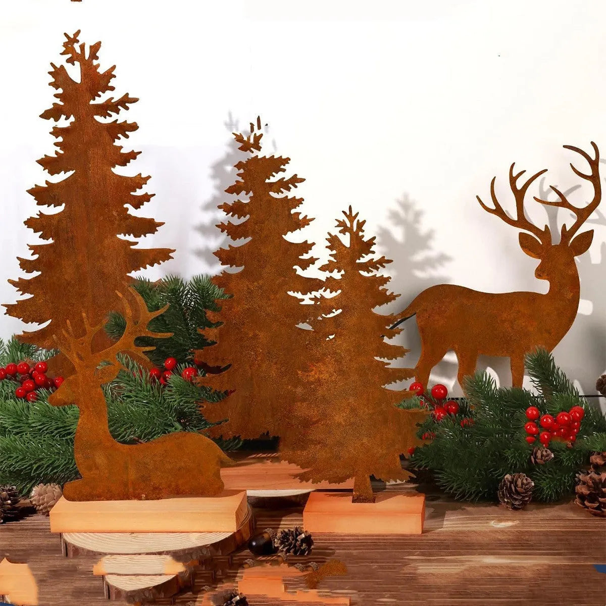 Set of three rustic iron metal Christmas tree and elk silhouette ornaments on a wooden surface.