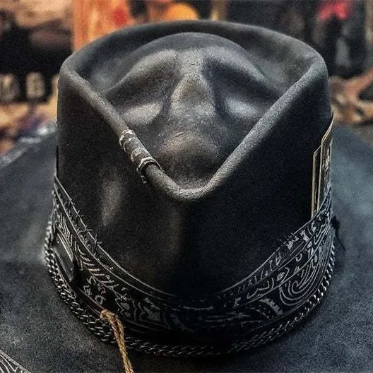 Handmade black wool felt skull hat with a pointed conical crown on a plain background.