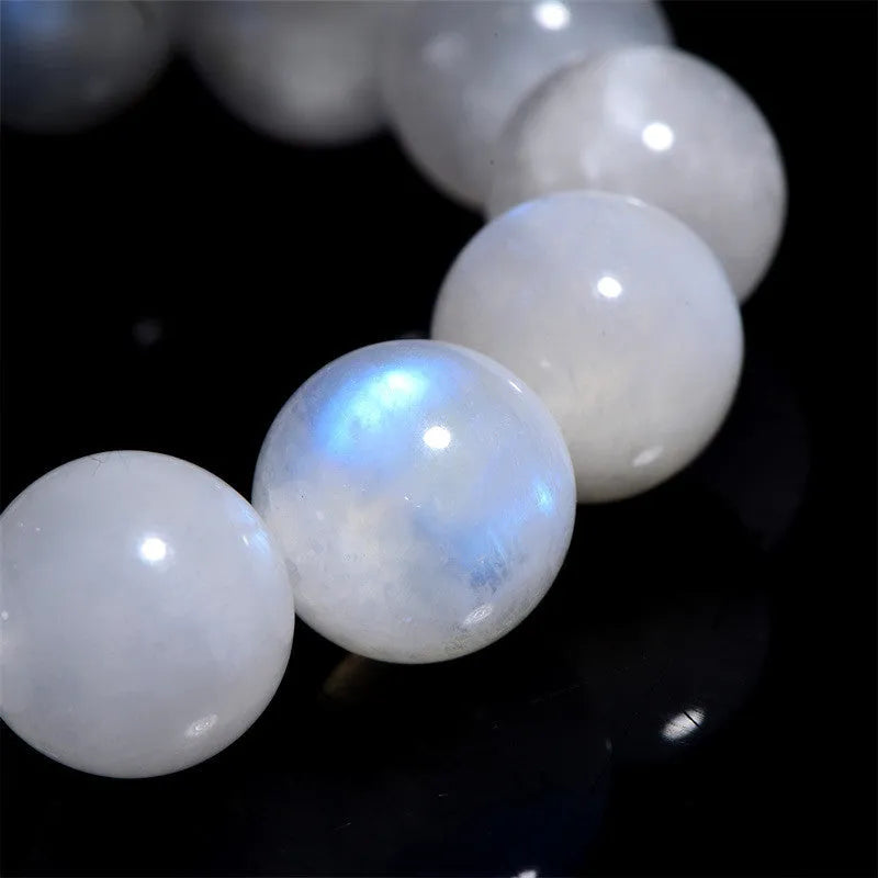 Natural blue moonlight round bead moonstone bracelet on a wrist, showing polished stones.