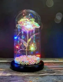 Artificial gold rose in clear glass dome on black base with LED lights for home decor