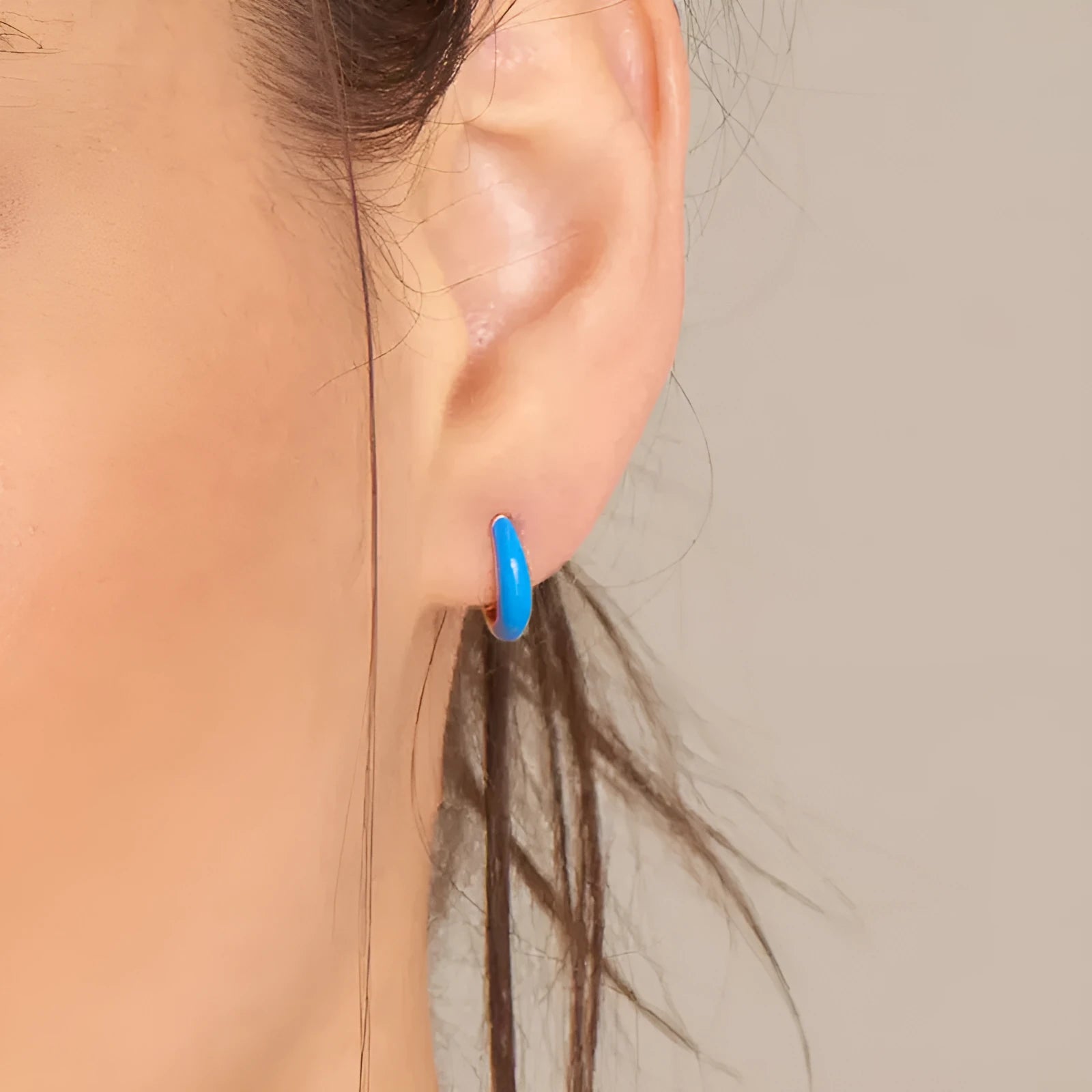 A pair of curved U-shaped drop earrings with a glossy light green oval and ring geometric design on copper wire.